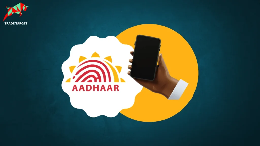 Hand holding a mobile phone with Aadhaar logo on a yellow circle against a teal background.